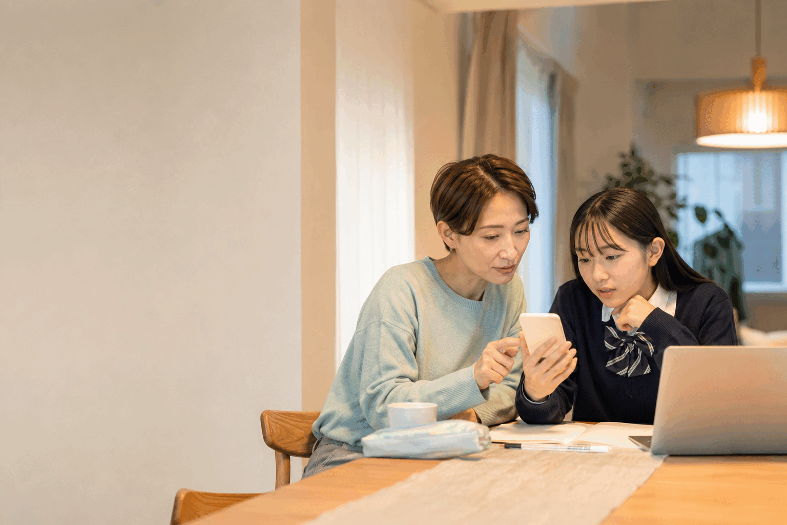 スマートフォンの画面を一緒に確かめる母親と娘