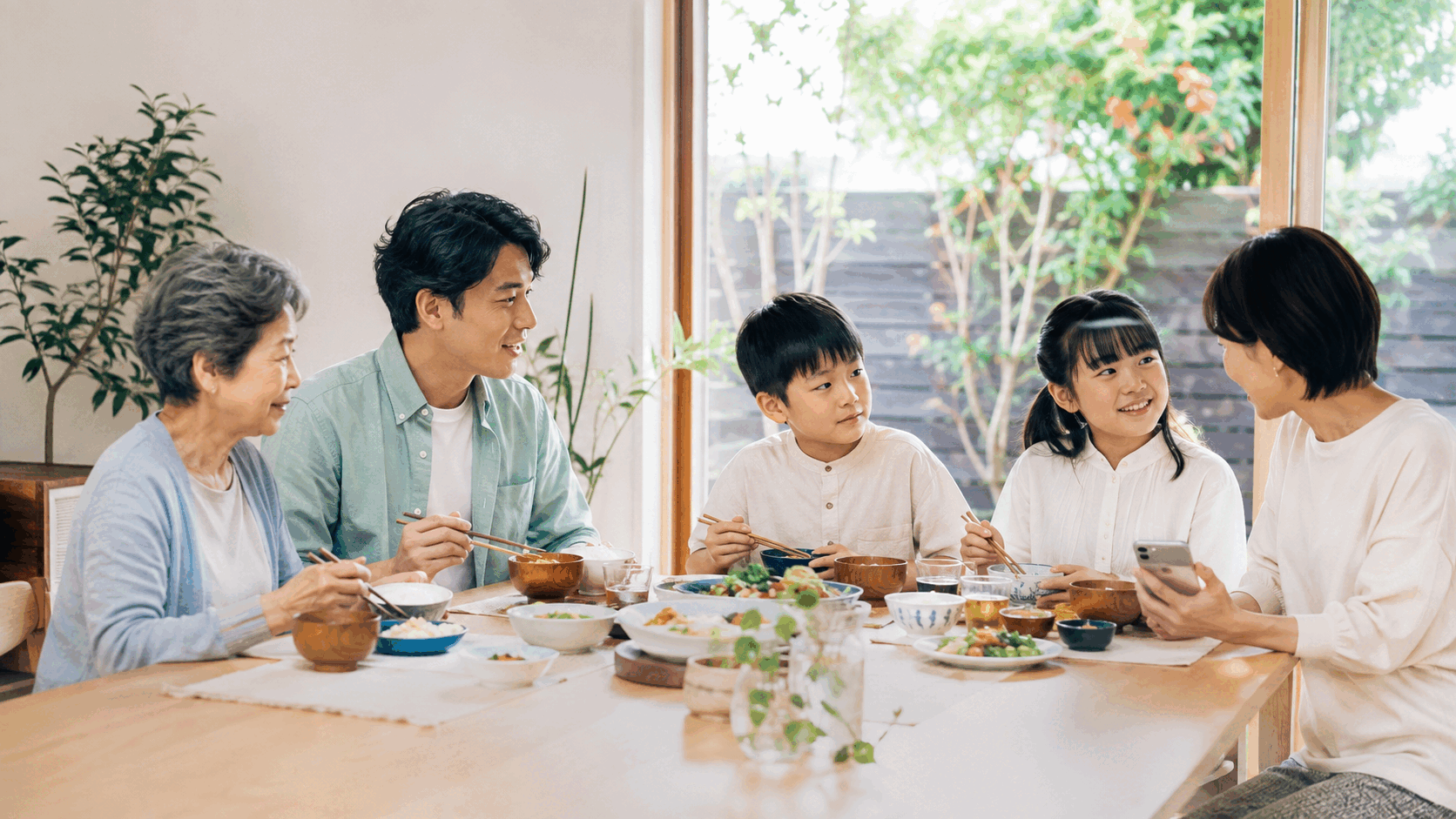 食卓を囲んで会話する三世代の家族